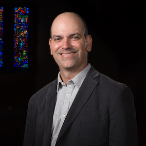 man in suit with stained glass window behind him
