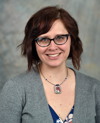 Close-up of a woman smiling in front of a backdrop.