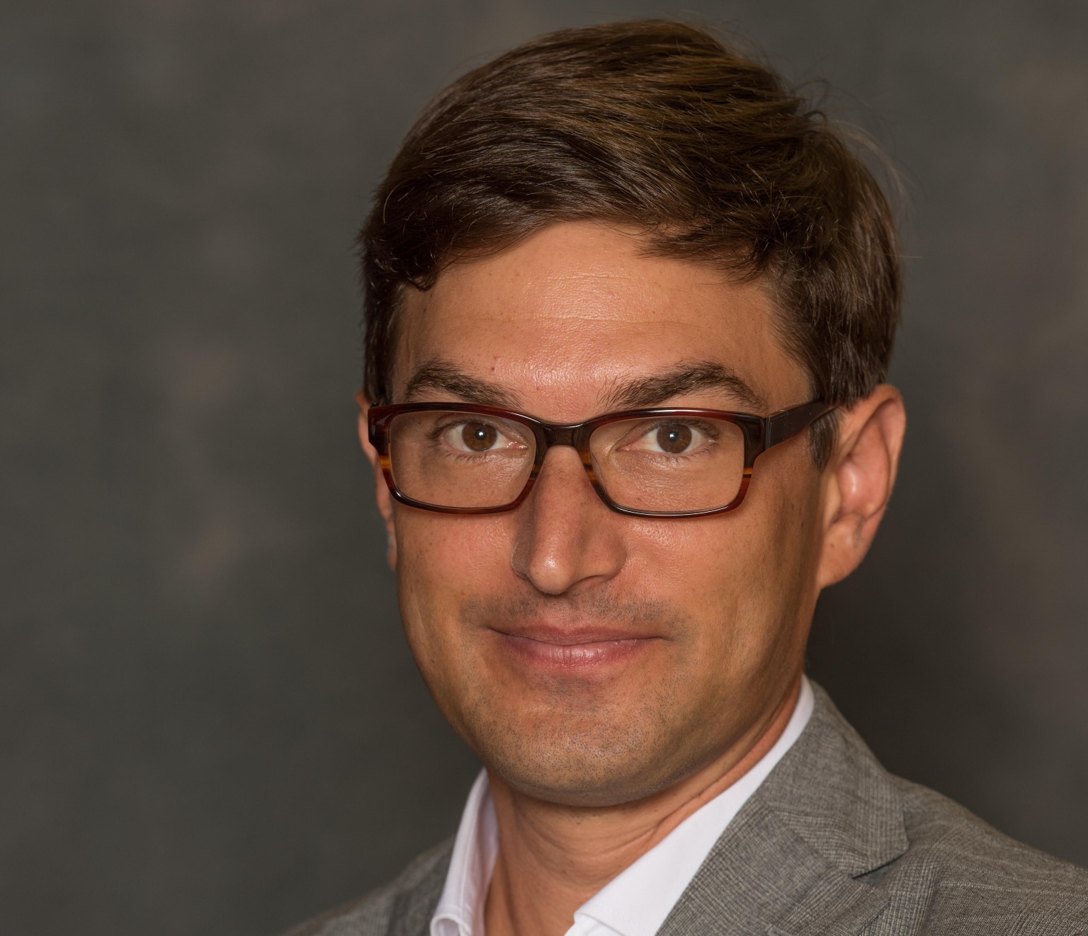 A picture of a man in a brown suit before a brown background.