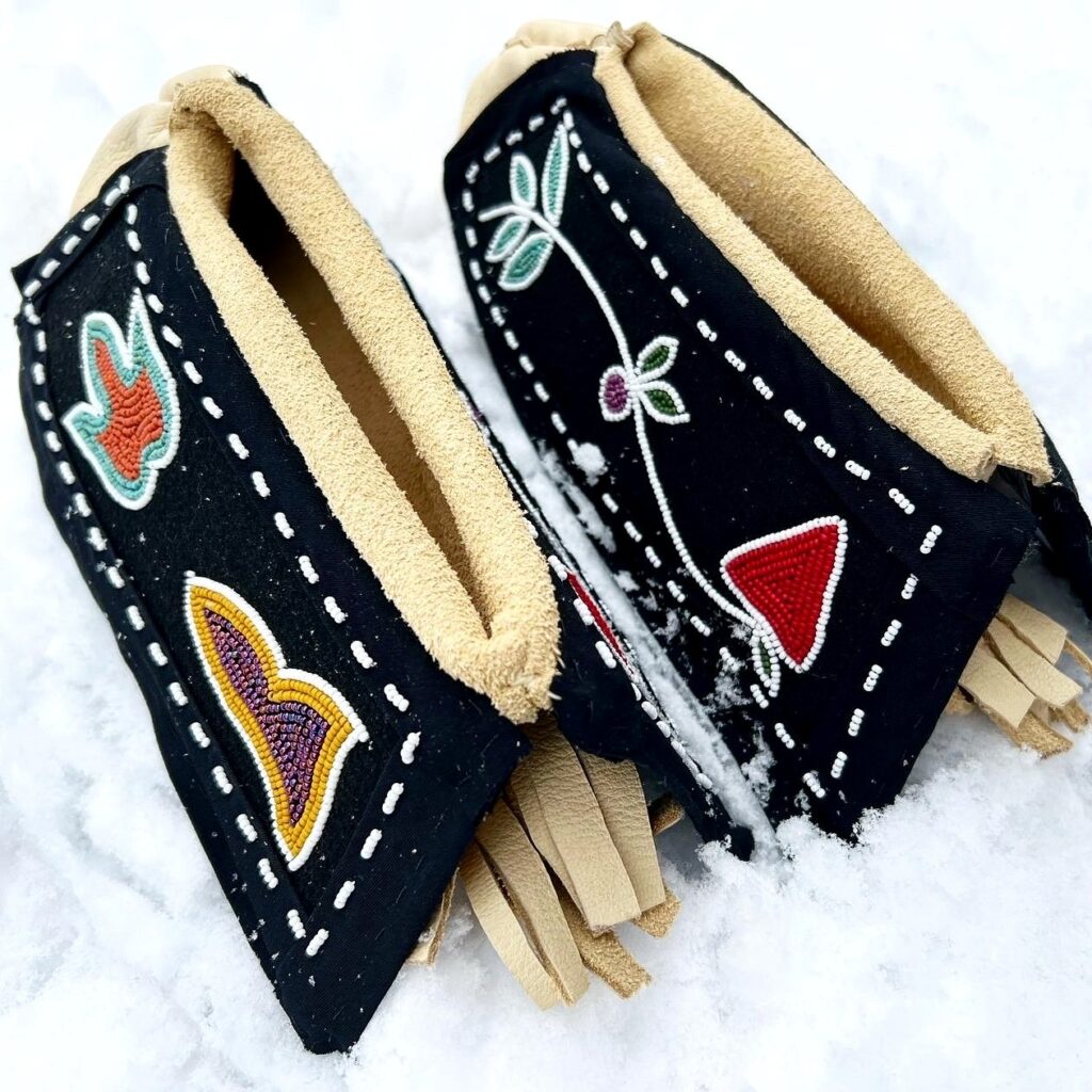 Black pouches with intricate floral and butterfly beadwork and a soft tan interior lining, with leather fringe peeking out from the ends.