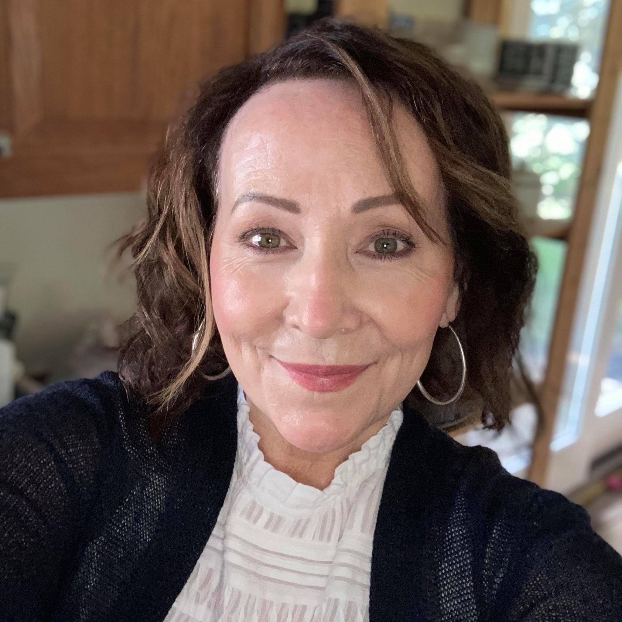 Close-up headshot of Carol Wilson-Duffy, Senior Academic Specialist in the English Language Center, with brown hair and hoop earrings, smiling in an indoor setting.